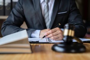 Close-up of an attorney reading law codes and studying the constitution to protect human rights, with law books and a gavel in view.