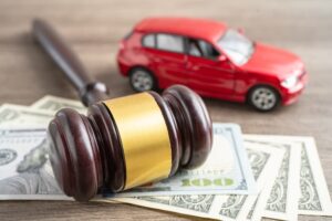 Hammer gavel judge and US dollar banknote money with car vehicle accident, insurance coverage claim lawsuit court case.