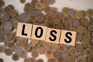 Wooden cubes displaying the word 'LOSS' on a wooden table, symbolizing financial loss, dementia, and mental health concepts.