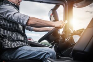 Truck driver at the wheel of a semi-truck, representing the driving and transportation industry.