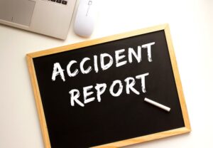 The words 'ACCIDENT REPORT' written in chalk on a slate board on an office desk.