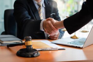 Businessman shaking hands with partner lawyers discussing a contract agreement, symbolizing legal advice and justice.