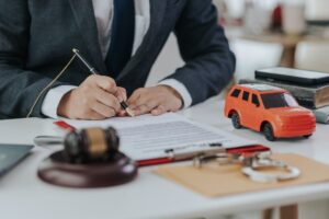 Judge's hand with car model, legal documents, and gavel