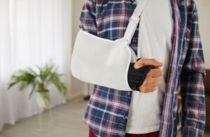 Close-up of male patient with a support brace and sling bandage after arm surgery, showing treatment for an injury.