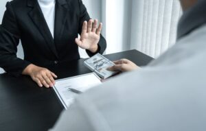 Businesswoman refusing a money-filled envelope offered during an investment deal