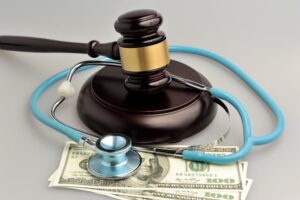 Stethoscope with judge gavel, money on gray background