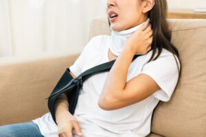 Woman with leg, neck, and arm splints sitting in a living room, recovering from an accident injury, symbolizing social security and health insurance.