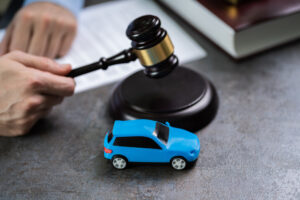 Close-up Of A Small Red Car In Front Of Judge Holding Mallet