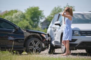 Sad female driver speaking on sellphone on street side calling for emergency service after car accident. 