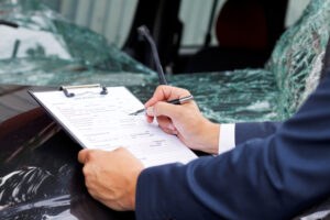 Well dressed insurance assessor inspecting damaged vehicle