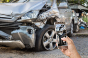 Close up hand of woman holding smartphone and take photo of car accident